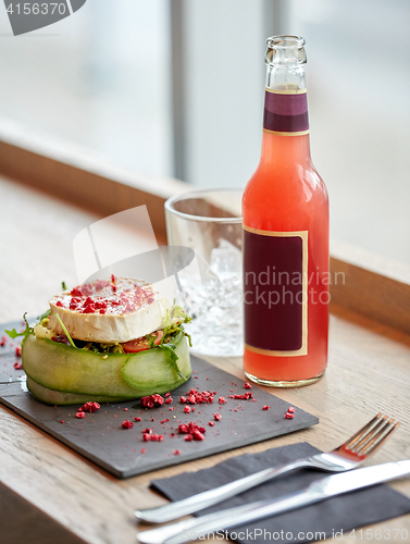 Image of salad, bottle of drink, glass and cutlery on table