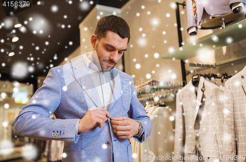 Image of happy young man trying jacket on in clothing store