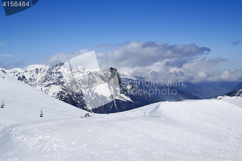 Image of Snowboarder jumping in terrain park at snow mountain on sun wint