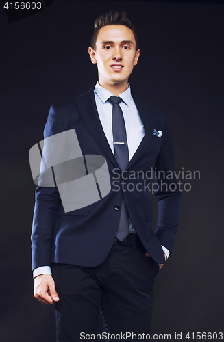 Image of young pretty business man standing on black background, modern h