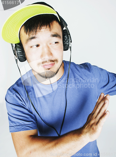 Image of young asian man in hat and headphones listening music on white b