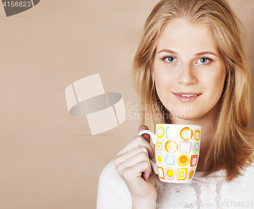 Image of young cute blond girl drinking coffee close up on warm brown bac