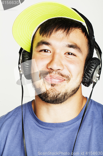 Image of young asian man in hat and headphones listening music on white b