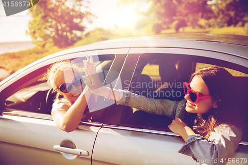 Image of happy teenage girls or women in car at seaside