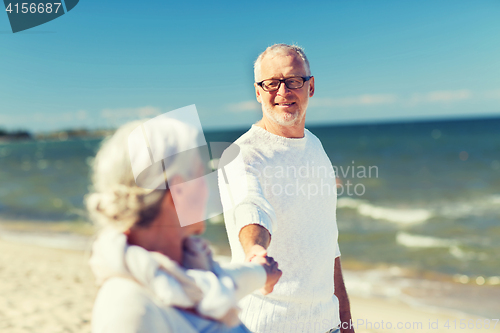 Image of happy senior couple holding hands on summer beach