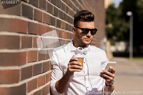 Image of man with smartphone and coffee cup on city street