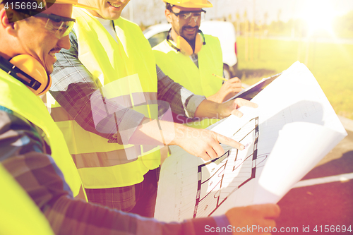 Image of close up of builders with blueprint at building