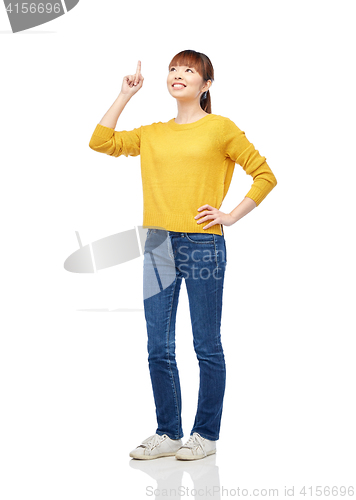 Image of happy asian woman pointing finger up over white