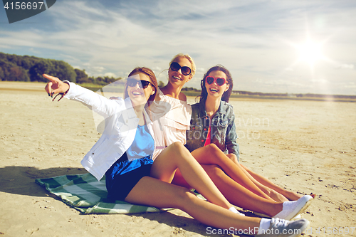 Image of group of smiling women in sunglasses on beach