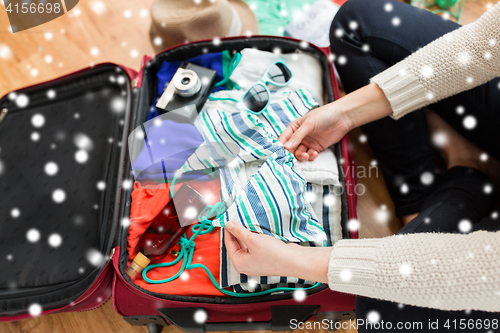 Image of close up of woman packing travel bag for vacation