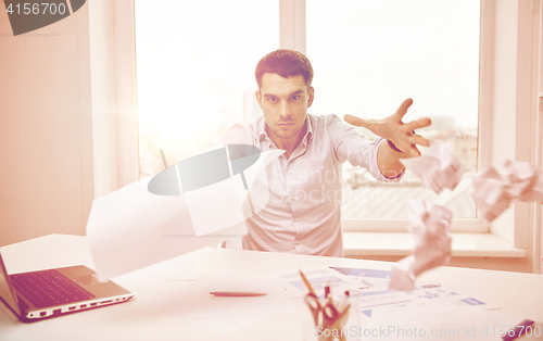 Image of angry businessman throwing papers in office