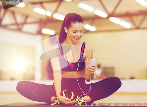 Image of smiling woman stretching on mat in the gym