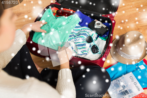 Image of close up of woman packing travel bag for vacation