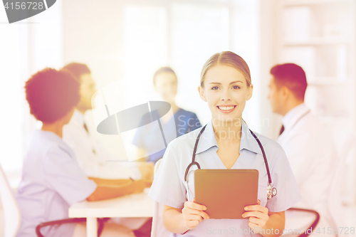 Image of happy doctor with tablet pc over team at clinic