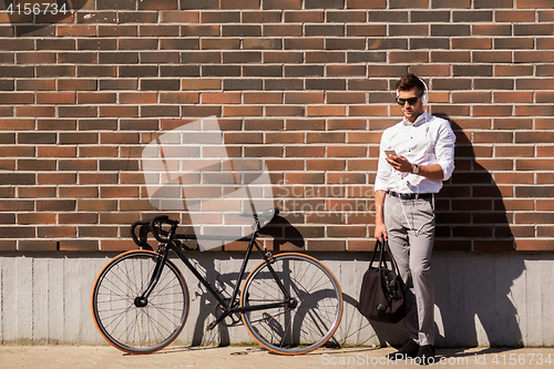 Image of man with headphones, smartphone and bicycle