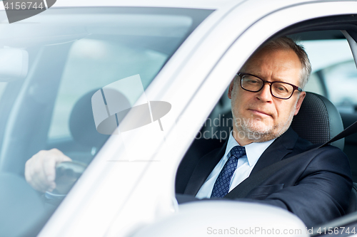 Image of happy senior businessman driving car