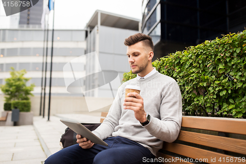 Image of man with tablet pc and coffee on city street bench