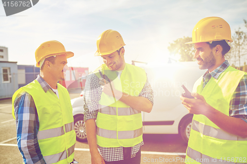 Image of happy male builders in vests with walkie talkie