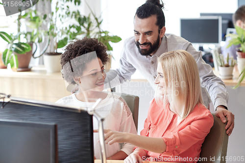 Image of happy creative team with computer in office