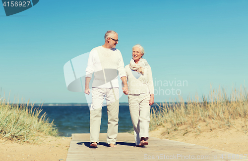 Image of happy senior couple holding hands on summer beach