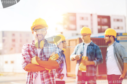 Image of group of smiling builders in hardhats outdoors