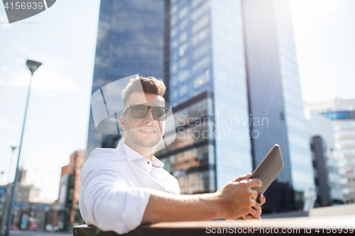 Image of man with tablet pc sitting on city street bench