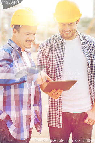 Image of smiling builders with tablet pc outdoors