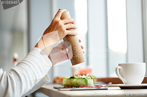 Image of woman with salt shaker and salad at restaurant