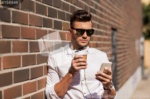 Image of man with smartphone and coffee cup on city street