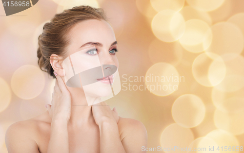 Image of beautiful woman touching her neck over lights