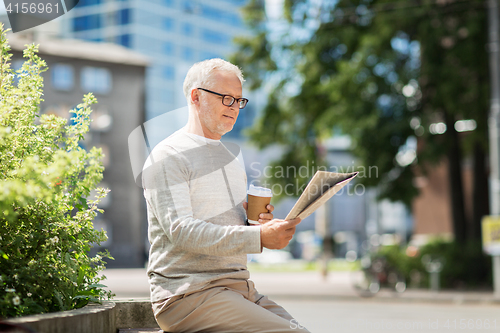 Image of senior man reading newspaper and drinking coffee