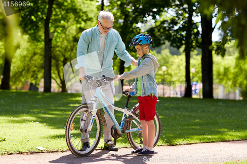 Image of grandfather and boy with bicycle at summer park