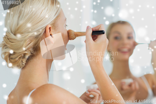 Image of woman with makeup brush and powder at bathroom