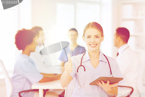 Image of happy doctor with tablet pc over team at clinic