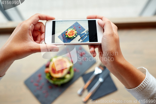 Image of hands with smartphone photographing food