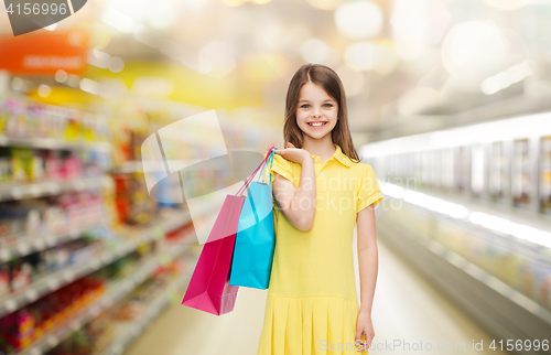 Image of smiling girl with shopping bags over supermarket