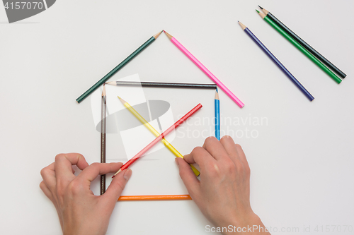 Image of Women\'s hands are building a house from pencils