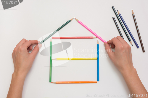 Image of Hands close-up build a house on a piece of paper from the crayons