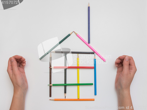 Image of Female hand made of pencils on paper funny house