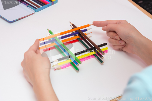 Image of She builds a well of pencils on a sheet of white paper, close-up
