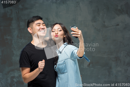 Image of Portrait of smiling Korean couple on a gray