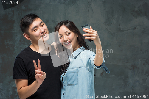 Image of Portrait of smiling Korean couple on a gray