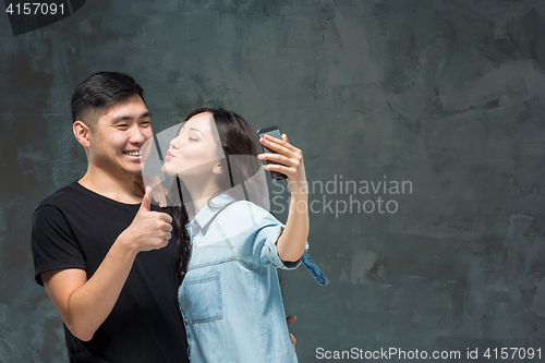 Image of Portrait of smiling Korean couple on a gray