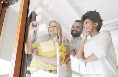 Image of happy creative team writing on stickers at office