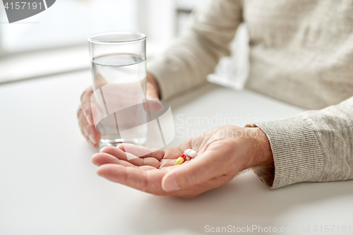 Image of close up of old man hands with pills and water