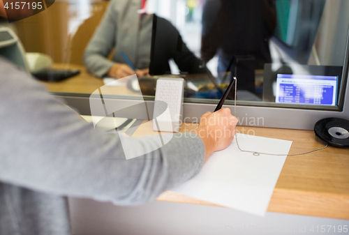 Image of customer writing application at bank office