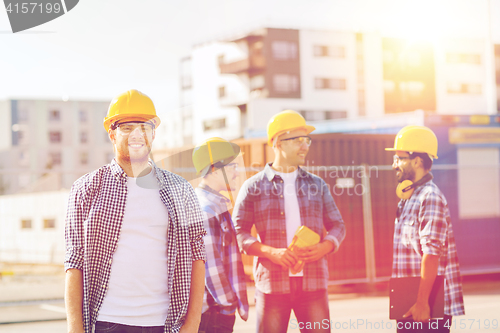 Image of group of smiling builders in hardhats outdoors