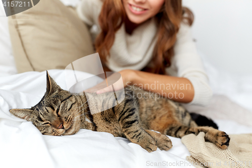 Image of happy young woman with cat lying in bed at home