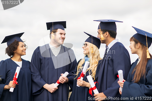 Image of happy students in mortar boards with diplomas