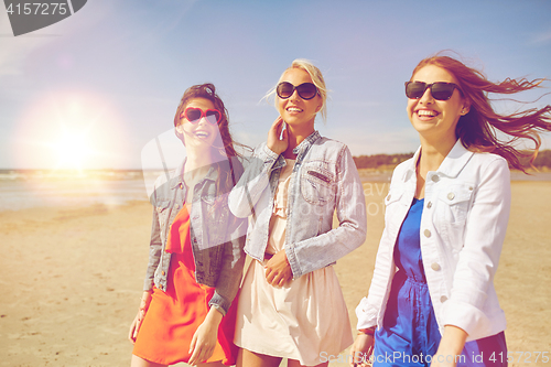 Image of group of smiling women in sunglasses on beach